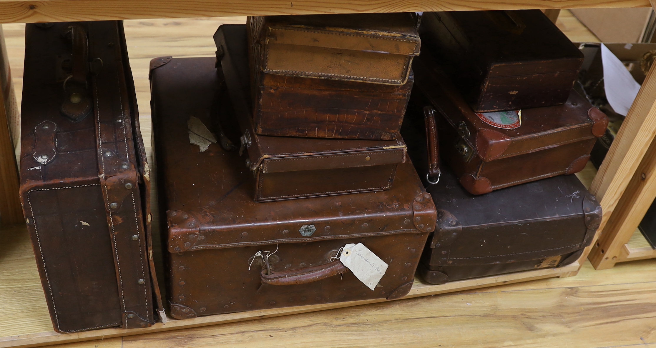 Seven vintage leather suitcases and a leather writing box (locked), the largest 60cm wide